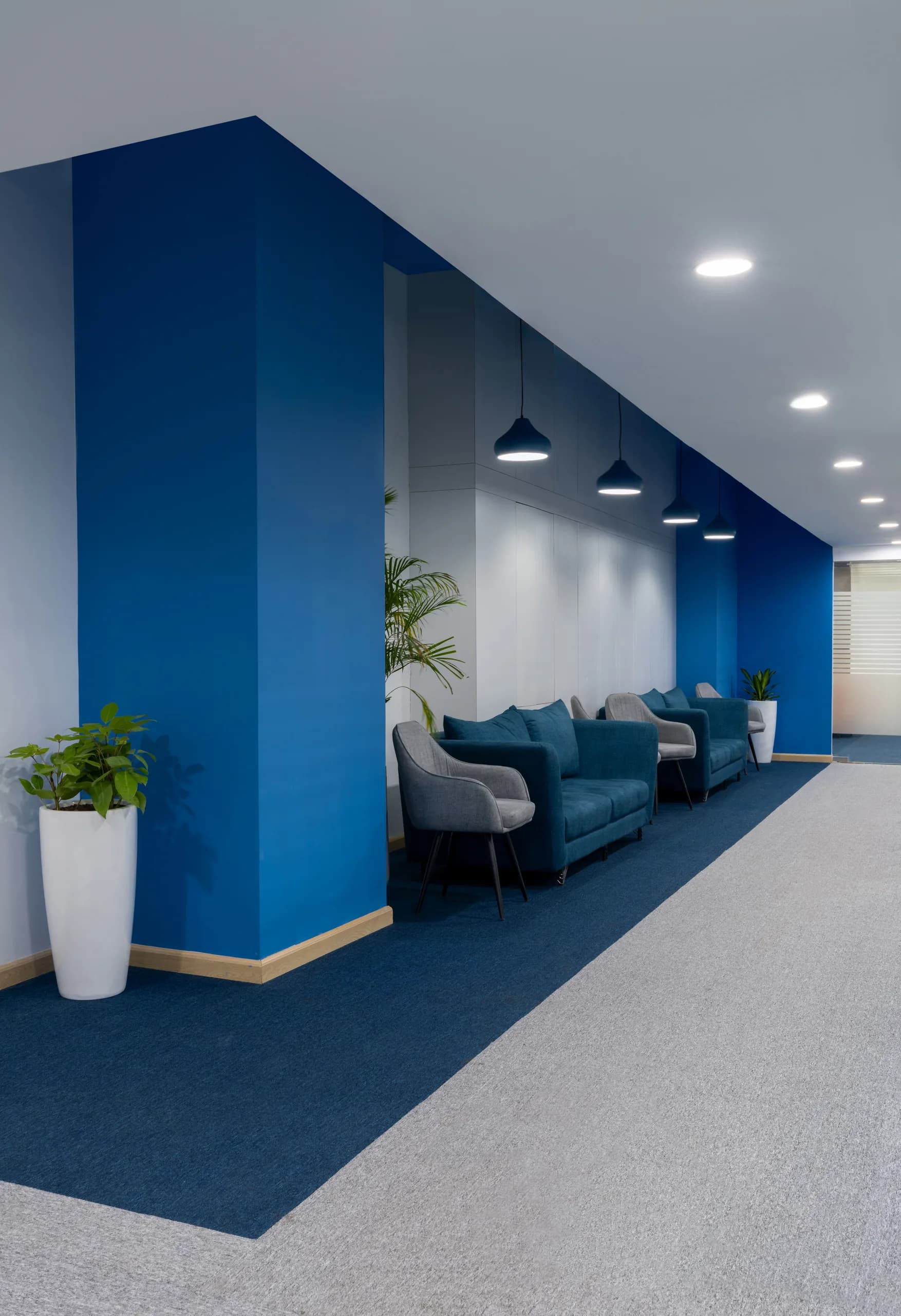 A blue column and waiting lounge with teal sofas, Blue Grid Workspace